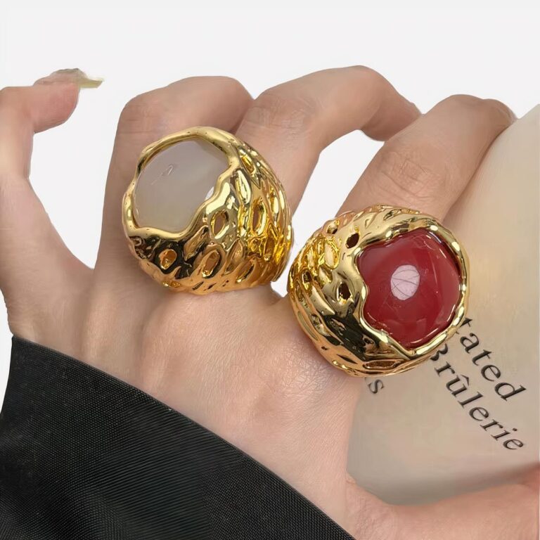 Main avec deux grosses bauges épaisses style vintage : une rouge et une blanche.