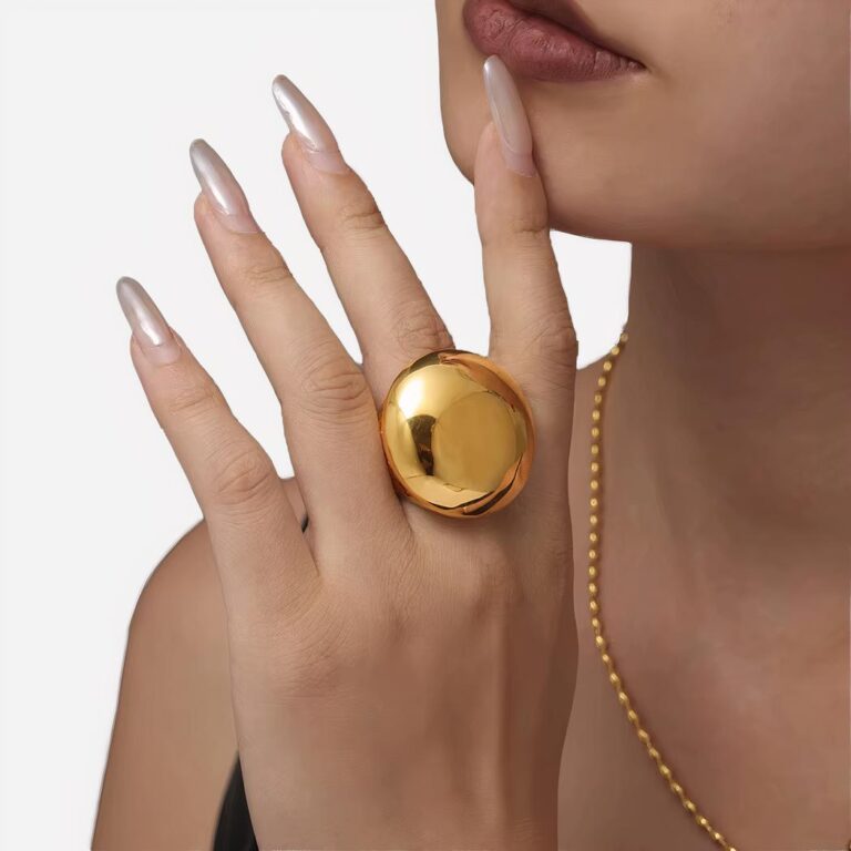 Main de femme qui porte une bague maxi ronde grande taille épaisse large dorée