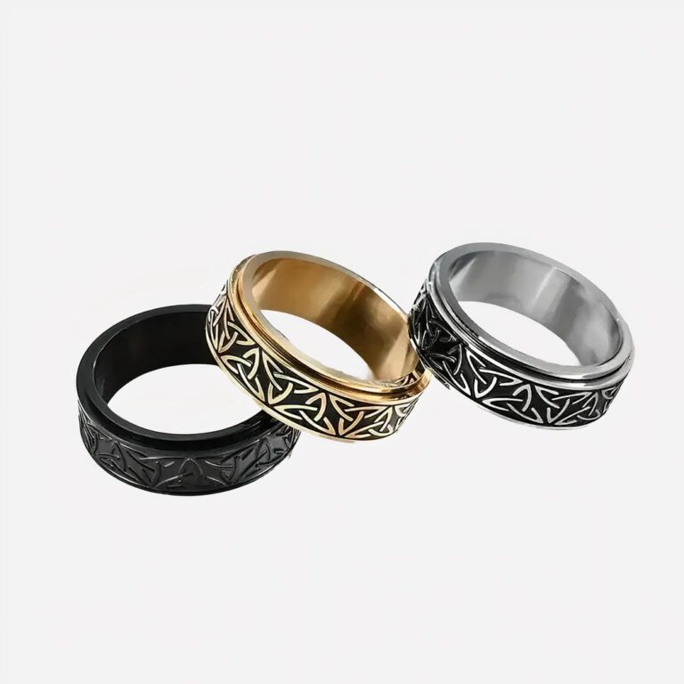 Bague viking homme rotative en acier inoxydable Photo de trois bagues viking pour hommes, anneaux rotatifs en trois couleurs, un noir, un doré et un argenté posés sur un fond blanc
