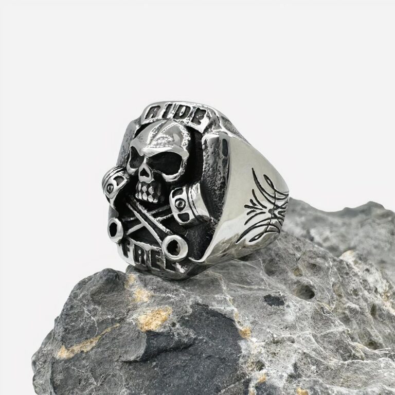 Bague tĂªte de mort homme style motard Photo d'une bague chevalière argentĂ©e Ă tĂªte de mort en relief sur une pierre grise, le tout sur fond blanc