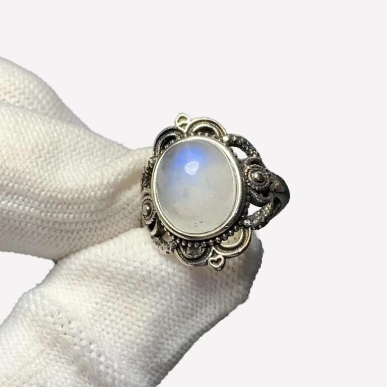 Bague vintage femme en argent sertie d'une pierre de lune, tenue par une main gantée