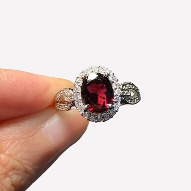 Bague marquise vintage en argent et grenat avec des zircons, tenue par une main.