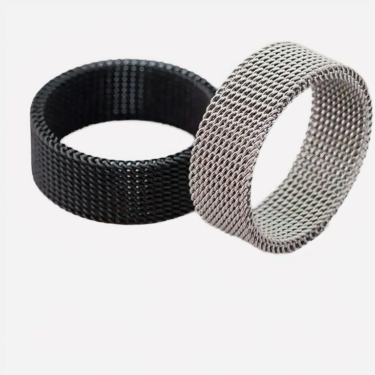 Bague homme moderne en maille d'acier Photo de deux bagues modernes pour homme en maille d'acier l'une noire et l'autre argentée sur un fond beige marbré