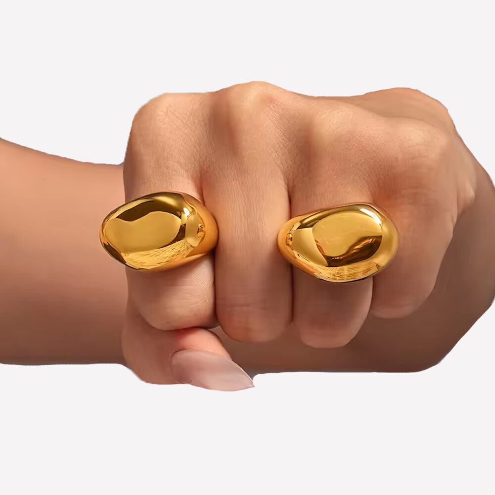 Bague dorées en forme de galet sur une main en forme de poing