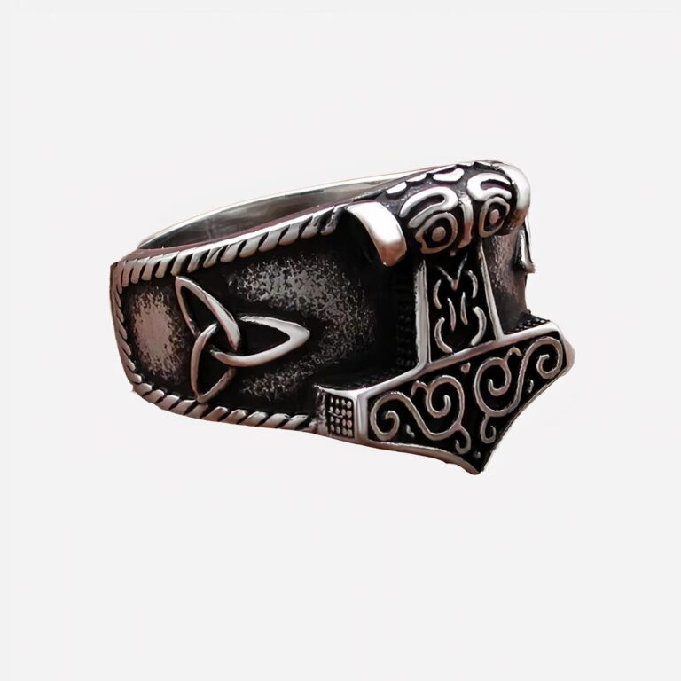 Photo d'une bague viking représentant le marteau de Thor sur le dessus, le fond est un revêtement couleur bois foncé