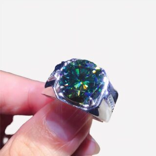 Photo d'une bague réglable pour homme en argent sterling et moissanite bleue et verte entre les doigts d'un homme sur un fond violet foncé