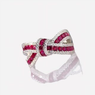 Photo d'une bague noeud en argent, rubis et zirconiums sur un plan incliné blanc brillant et fond noir