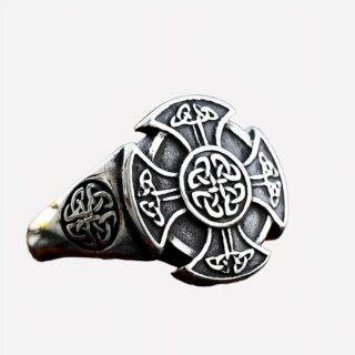Photo d'une bague à noeuds celtiques et croix viking en argent sterling vieilli sur une terre rouge foncée et fond marron