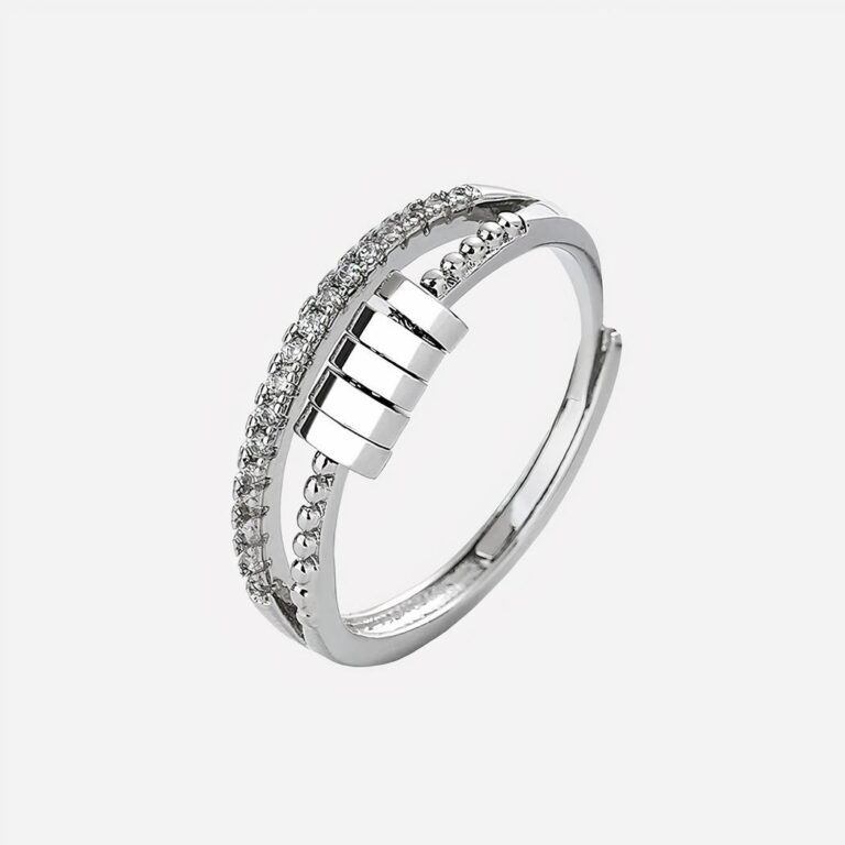 Bague argentée avec breloques sur fond gris.