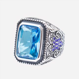 Bague bleue avec motifs sur fond blanc.