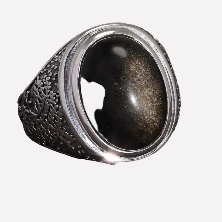 Bague argentée avec pierre noire sur fond gris.