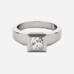 Bague argentée carrée sur fond blanc.